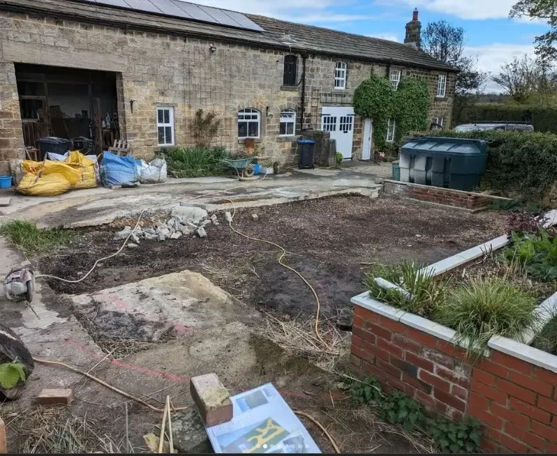Before: bare concrete farmyard beside the cottage, ready for excavation