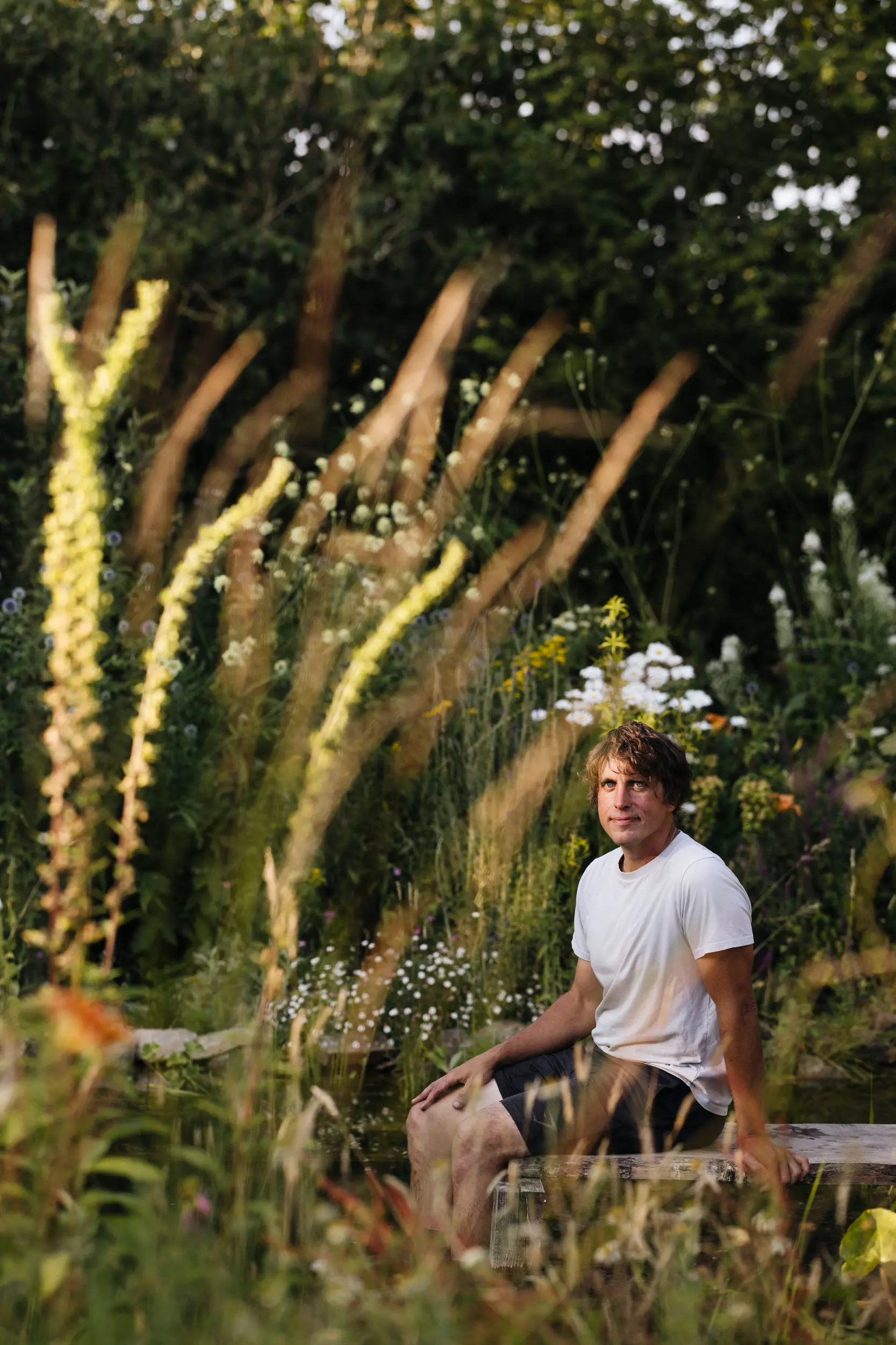 Will Tomson seated by a wildlife pond among tall planting, featured as a 2026 House & Garden Awards Rising Star nominee